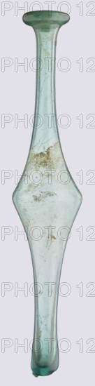 Unguentarium, unknown eastern workshop, Goluchów Greater Poland Voivodeship, with an elongated belly and a long neck, 3rd–4th century AD, unknown type of site/place of origin, vessel, height 36 cm, width 7 cm, A tall, elongated glass object with a narrow neck flaring into a rounded rim at the top and tapering into a rounded end at the bottom, featuring a widened, diamond-shaped midsection; the glass is translucent with a pale greenish-blue tint and shows areas of cloudiness, surface scratches, and irregular patches of beige and brown residue or staining; the surface has small imperfections and variations in thickness, and the overall shape is symmetrical along its vertical axis.