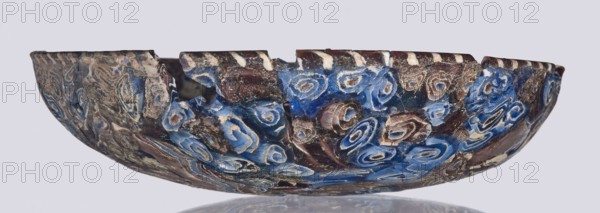 Bowl, Egyptian workshop; mosaic glass bowl with flat bottom, walls widening toward the top then narrowing at the rim, cut flat at the top. Made of thick glass using the mosaic technique with floral patterns in blue, purple, yellow, green, and white. Type: Isings form 1. Semicircular bowl; sagging on the form; 1st century, Roman Empire 27 BC–476; vessel; height 3 cm, width 13.5 cm.