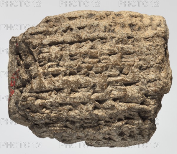 Cuneiform tablet with receipt, unknown Babylonian official role classification of creator, cuneiform tablets, Neo-Babylonian document, trade, Rectangular tablet, slightly convex, horizontally oriented. Three corners broken off; cracks on the lower and left sides; 9 lines of cuneiform text on the obverse, 2 on the lower side, 9 on the reverse. 6th century BC; Neo-Babylonian period, Babylonia Iraq, Southern Mesopotamia, administrative document, height 3.8 cm, width 4.5 cm, thickness 2 cm, A rough, irregularly shaped stone with a textured, pitted surface fills the frame, showing layered, incised grooves and ridges across its face; the stone is primarily beige and light brown with areas of darker brown and small flecks of off-white, and there is a small area of red on one side.