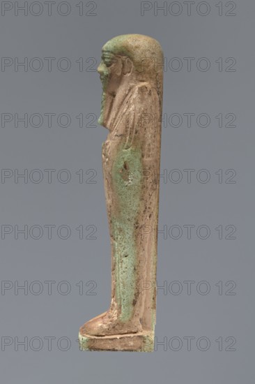 Ushabti, unknown creator; Hor-em-saf ca. 664–525 BC. Mummy-shaped figurine made of green faience. Stocky build, standing on a base, supported at the back by a pillar/pilaster. Arms crossed on the chest; from under the shroud only the hands clenched into fists are visible. Right hand holds a hoe, left hand a pickaxe; a basket on a single string hangs over the left shoulder. Engraved tools. Smooth three-part wig, straight braided beard. Large eyes with downcast eyelids, prominent mouth with a slight smile, wide nose. Engraved inscription in two columns on the front of the legs reading: Shd Osiris Hor-em-saf born of T-ate-iset. 664–525 BC; Late Period, 26th Dynasty, Egypt. Type: shabti. Height 10.6 cm; width 3.2 cm., A slender vertical statuette of a human figure shown in profile, standing on a rectangular base with a slightly forward-leaning posture; the figure wears a close-fitting headdress and a long garment that falls to the feet, and the arms appear crossed or held close to the body...