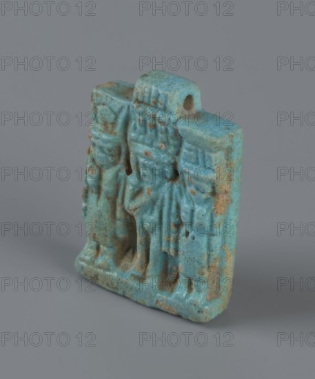 Amulet – plaque with a triad of deities: Harpocrates Horus, Isis, Nephthys. Amulet in the shape of a plaque with a triad of deities standing on a base. In the center is a figurine of Horus, on the left Isis, on the right Nephthys. The back of the plaque is flat. Pendant above the upper edge. 664–30 BC; Late Period–Ptolemaic Period probably, Egypt. Material: amulet. Dimensions: height 3.3 cm, width 2.2 cm, depth 0.7 cm., A small carved object with a rough, weathered surface in shades of blue and turquoise with patches of brown residue, showing a group of three upright, stylized figures in relief; the top edge has a rounded protrusion with a hole, and the base is slightly uneven, all set against a plain gray background.
