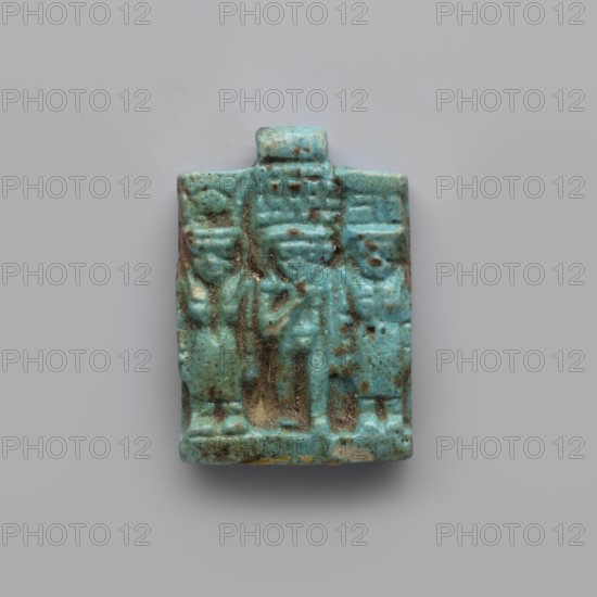Amulet – plaque with a triad of deities, Harpocrates Horus, Isis, Nephthys. Amulet in the shape of a plaque with a triad of deities standing on a base: center figurine of Horus, left Isis, right Nephthys. Back of the plaque is flat; pendant above the upper edge. Date: 664–30 BC, Late Period–Ptolemaic Period probable. Find country: Egypt. Object type: amulet. Dimensions: height 3.3 cm; width 2.2 cm; depth 0.7 cm., A small rectangular object with a raised relief depicting a group of three standing figures, rendered in a turquoise blue with areas of darker brownish-green patina and small pale beige spots, showing worn and pitted surfaces and textured details in the figures' clothing and headpieces, set against a smooth light gray background.
