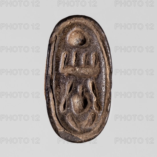Amulet — seal with cartouche of Menkheperre; maker, cartouches, Scen.Gal.Eg.; inscription: Menkheperre cryptograms; depiction related to Tuthmosis III ruler of Egypt; ca. 1479–1425 BC; convex handle; ca. 1550–1069 BC, New Kingdom, Egypt; seal/amulet; height 1.3 cm, width 2 cm., An oval, carved object with a textured surface in shades of brown and dark brown against a light gray background, showing raised and recessed shapes including rounded bumps and elongated indentations arranged vertically, with visible worn edges and a slightly glossy sheen.