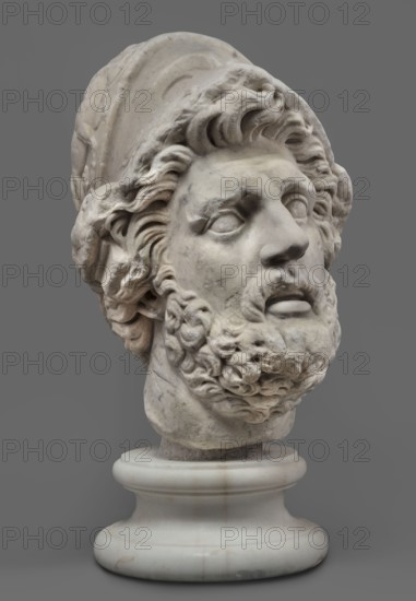 Head of Menelaus from the Menelaus Carrying the Body of Patroclus group, unknown artist. Head of a bearded man wearing a helmet, with an expressive face shown by wide-open eyes and parted mouth, emphasized by chiaroscuro effects from lush locks of beard and hair emerging from under the helmet contrasted with smooth facial skin. The face depicts a man experiencing dramatic moments. The helmet is adorned with relief decoration: on each side a centaur fighting a Greek, and below on the edge a triton figurine. The sculpture is a Roman copy of the head from a Hellenistic bronze composition depicting Menelaus with the body of Patroclus. Menelaus, Helen's husband, first fights to retrieve the deceased's body and then carries it from the battlefield for burial according to ritual. The death of Patroclus, Achilles' friend, is an important moment in the Trojan War, bringing Achilles back into the fight and influencing the war's outcome. Frequently reproduced in Roman sculpture. Date: 1st half of...