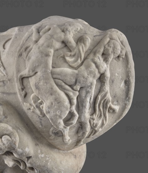 Head of Menelaus from the Menelaus Carrying the Body of Patroclus group, unknown artist. Head of a bearded man wearing a helmet, with an expressive face shown by wide-open eyes and parted mouth, emphasized by chiaroscuro effects from lush locks of beard and hair emerging from under the helmet contrasted with smooth facial skin. The face conveys a man experiencing dramatic moments. The helmet is adorned with relief decoration depicting fantastic creatures: on each side a centaur fighting a Greek, and below on the edge a triton figurine. The sculpture is a Roman copy of the head from a Hellenistic bronze composition depicting Menelaus carrying the body of Patroclus. The scene reflects Menelaus retrieving and carrying Patroclus’s body after his death in the Trojan War. Frequently reproduced in Roman sculpture. Dated broadly to the 1st half of the 2nd century AD reign of Hadrian, 117–138. Roman Empire, sculpture, weight 78.5 kg., The image shows a close-up of a carved stone relief in pale ...