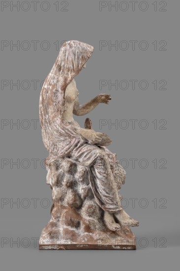 Figurine of Leda with a Swan, A woman sits on a rock and feeds a swan standing next to her. She is dressed in a cloak thrown over her head and back, which falls along her body and completely envelops her legs, leaving the rest of her body exposed. In her right hand, resting on her knees, she holds a platter. With her left hand, bent at the elbow and extended, she holds it above the swan, which rests on her exposed hip, its head extended towards her. The woman bows her head and looks at it. The swan has outstretched wings. The woman's sandaled feet do not rest on the rock but dangle. The square base forms one with the rock. Cloak painted pink. Mid-3rd century BC, Myrina; figurine; height 24 cm, width 15 cm, depth 12 cm, weight 0.56 kg., A weathered sculptural figure seated on a rough, rock-like base, shown in profile facing right, with a draped hood or cloak falling over the head and back; the figure's exposed arm is extended forward with the hand slightly open, and the legs are relaxed...