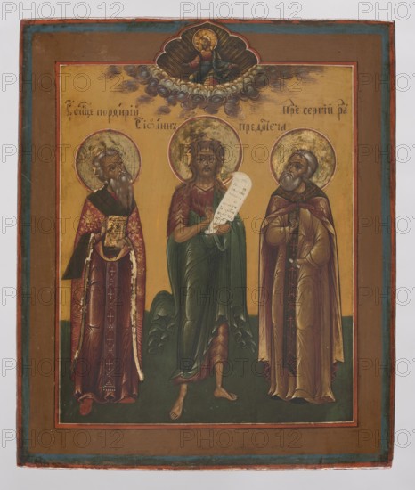 Icon: Saints John the Baptist, Porphyry, and Sergius of Radonezh before Christ, Northern School 1500–1917. In the center St. John the Baptist, dressed in an animal skin and a cloak, holds an unrolled scroll. On the left is St. Porphyry in bishop's robes; on the right St. Sergius of Radonezh in monk's robes. Above, on the axis, Christ Pantocrator is shown knee-deep in clouds, blessing with both hands. The icon is meticulously rendered with attention to detail; colors are contrasting—predominantly cinnabar, ochre, and green. Identifying inscriptions appear in the background of the central part. 19th century, Russia. Dimensions: height 31.0 cm; width 26.2 cm., A painted panel showing a religious scene with three standing haloed figures against a golden background, framed by a brown border with blue and red inner edges; the central figure is barefoot, wearing green and red draped robes and holding a pale scroll, flanked by two bearded figures in ornate robes and cloaks—one on the left wear...