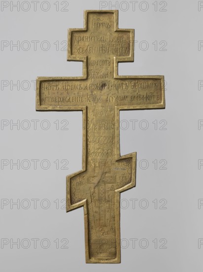 Cross: Crucifixion of Christ; Old Believers workshop; subjects: Adam Bible, angels, Jesus Christ Bible, God the Father iconography, the Holy Spirit iconography, skull iconography, crosses, moon iconography, Lord of Hosts iconography, Jerusalem Israel/Palestine, sun iconography, Dove Bible; inscriptions; Crucifixion iconography. The obverse presents iconography typical of Old Believers/Pop-Rites objects: the crucified Christ, above him the Lord of Hosts blessing from the clouds, below him the dove of the Holy Spirit with angels descending toward the Savior. The cross stands on symbolic Golgotha with a cave containing Adam's skull and is set against a symbolic representation of Jerusalem. On the reverse is an apotropaic prayer to the Holy Cross. 19th century, Russia. Cross; height 36.5 cm, width 18.5 cm., A metal cross-shaped object with a stepped design and beveled edges, shown against a plain light gray background; the surface of the cross has incised decorative patterns and shallow ca...