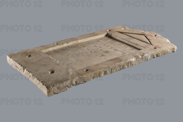 Small limestone stele with simple architectural decoration. Recessed epigraphic field surrounded by a wide strip. Simple pediment and acroteria. Remains of engraved guide lines made by a stonemason while designing the decoration. Traces of red paint highlighting elements of the pediment and on the top and side strips in the form of metopic decoration. Below the epigraphic field, an unidentified brownish, rounded shape. Side edges rather carelessly worked; back surface with very long tool marks. Object glued together from eight fragments; upper part not preserved. Six holes for mounting on the wall, probably made later for exhibition. Grave inscription in Greek. Date: 30 BC–1 AD beginning of the Roman period. Probable findspot: Tell el-Yahudiya . Height 48.8 cm, width 27.4 cm, depth 2.7 cm. Maker: unknown., A rectangular stone slab rests against a plain gray background, showing rough, worn edges and an uneven surface with a recessed rectangular panel in the center and a raised border ar...