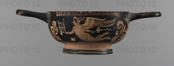 Red-figure bowl kylix, 3rd quarter of the 4th century BC, Apulia. Yellow clay tending to red with glossy black engobe; some elements painted white. Bowl with ring-shaped base with two vices attached to the rim horizontally; palmettes beneath the vices. Belly decorated with two scenes: Scene A — a young woman semi-reclining on the ground, facing left, holding a wreath in her left hand and a woven basket on her outstretched right hand; wearing a long smooth chiton, pearl necklace, double bracelets, hair in a bun covered by a kekryphalos. Scene B — Eros flying, facing left, holding a musical instrument in the right hand and a wreath with ribbon in the left; hairstyle and jewelry matching Scene A bun with kekryphalos, double bracelets, pearl necklace, with ankle bracelets and a diadem; entire figure has hermaphroditic features. Function: vessel kylix. Condition: numerous chips, engobe dull in places. Dimensions: height 5.1 cm, width 17.5 cm, depth 10 cm. Keywords: red-figure pottery, bowls...