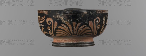 Red-figure bowl kylix, 3rd quarter of the 4th century BC, Apulia. Yellow clay tending to red with glossy black engobe; some elements painted white. Bowl with ring-shaped base with two vices attached to the rim horizontally; palmettes beneath the vices. Belly decorated with two scenes: Scene A: young woman semi-reclining on the ground, facing left, holding a wreath in her left hand and a woven basket on her outstretched right hand; wearing a long, smooth chiton, pearl necklace, double bracelets, hair tied in a bun with a kekryphalos. Scene B: Eros flying, facing left; in right hand a musical instrument and in left hand a wreath with a ribbon; hairstyle and jewelry like Scene A bun with kekryphalos, double bracelets, pearl necklace, ankles adorned with bracelets, head with a diadem; entire figure shows hermaphrodite features. Function: vessel kylix. Condition: numerous chips, engobe dull in places. Dimensions: height 5.1 cm, width 17.5 cm, depth 10 cm. Tags/subjects: red-figure pottery, ...