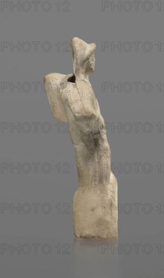 Terracotta gladiator figurine, unknown Southern Italian workshop, terracotta, male figurines. Figure of a gladiator ready for battle on a high base. Legs wide apart, left leg bent, right leg straight. On the calves are greaves reaching above the knees. In his right, bent hand he holds a dagger, and in the other a four-sided shield. He is dressed in a short draped tunic and wears a helmet. The Latin inscription PACILI is visible on the reverse of the base. Preservation condition: part of the base filled with plaster, partial shield and back of the head broken off, reflections, cracks. Date: 2nd–1st century BC, Southern Italy. Figurine. Height 13 cm, width 7 cm., A light-colored sculptural figure shown in profile against a neutral gray background, with an elongated vertical form and a defined head wearing a hood-like shape, a rounded back element projecting behind the upper torso, visible arm contours and rough textured surface with subtle variations in beige, cream, pale gray, and muted...