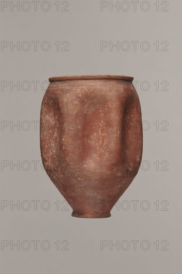 Rippled beaker miniature version, unknown Germanic workshop from Cologne?, hard-fired clay, fine-grained, with a small content of silvery mica, buff-pink-brown 5YR 6/4–6/6; grey-olive glaze 5YR 4/1–4/2, matte, covers the entire surface, slightly rough outside intentionally sandblasted; discolorations of the glaze above the foot left by fingerprints. Walls have six decorative dents. Minor damage to the rim, slight cracks. 2nd half of 2nd–3rd century, Cologne, vessel, height 9.7 cm, diameter 5.5 cm., A large rounded clay vessel with a narrow base and a slightly flared rim, shown against a plain light gray background; the vessel has a weathered surface with a reddish-brown base color, areas of darker brown, and lighter tan and beige speckling and mottling across its body, with subtle vertical indentations on either side and a rough, matte texture.