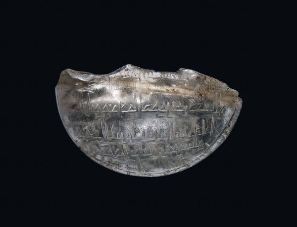 Fragment of an amulet with an Arabic inscription, inscription probably with magical meaning, Islamic art, Arabic culture, amulet with Arabic inscription, 11th–12th century, Egypt; height 1.1 cm, width 2.5 cm, depth 0.9 cm, A translucent, crescent-shaped object with a glossy surface floats against a dark background; the object is mostly clear with cloudy white and pale beige areas, and it shows a few rough, chipped edges and surface scratches. Several shallow, linear incisions form repeating angular patterns across the object's face, and there are a few tiny brownish spots and inclusions visible within the material. The overall colors visible are clear/translucent, white, beige, brown, and dark blue-black from the background.