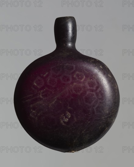 Pilgrim's bottle, Islamic/Arabic, Ayyubid dynasty 12th–13th century, Syria/Egypt/Middle East probable origin. Violet manganese glass. The belly is widened at the arms, which merge into a cylindrical, slightly convex neck with a narrow opening. One wall bears a star motif with a rosette in the middle and a palmette; the other and the side arms show a honeycomb motif. Vessel; height 11.8 cm, width 9.1 cm, depth 4.2 cm., A rounded object with a short neck and rounded top, shown against a plain gray background, with an overall deep purple surface that transitions to dark brown and black toward the edges; the surface shows a few lighter purple hexagonal patterns, several small scratches and scuffs, and a few pale worn spots.