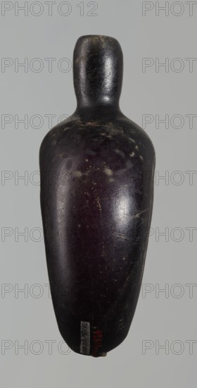 Pilgrim's bottle, gift, Islamic art; Arabic/Islamic culture; Ayyubid dynasty 1171–1341; geometric ornament. The belly is widened at the arms, which merge into a cylindrical, slightly convex neck with a narrow opening. On one wall there is a star motif with a rosette in the middle and a palmette; on the other and on the side arms there is a honeycomb motif. Violet manganese glass. 12th–13th century. Syria?, Egypt?, Middle East? Vessel. Height 11.8 cm; width 9.1 cm; depth 4.2 cm., A single elongated rounded object with a narrow top and wider tapered body, photographed against a plain light gray background; the object has a smooth, worn surface showing scuffs and small scratches and appears predominantly very dark brown to black with subtle areas of deep purple and hints of tan or beige marks where the surface is worn.