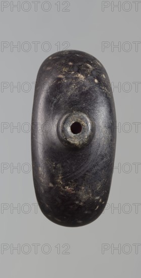 Pilgrim's bottle, Islamic art, Arabic/Islamic culture, Ayyubid dynasty 12th–13th century. The belly is widened at the arms, which merge into a cylindrical, slightly convex neck with a narrow opening. One wall has a star motif with a rosette in the middle and a palmette; the other wall and the side arms have a honeycomb motif. Violet manganese glass. Syria/Egypt/Middle East place of origin uncertain. Vessel; height 11.8 cm, width 9.1 cm, depth 4.2 cm., A smooth, elongated dark object with an oval, pebble-like shape is centered against a pale grey background; its surface is primarily deep black with areas of dark brown and scattered patches of dull gold and lighter brown discoloration, and there is a raised circular knob near the center with a rounded hole in its middle showing a darker interior.