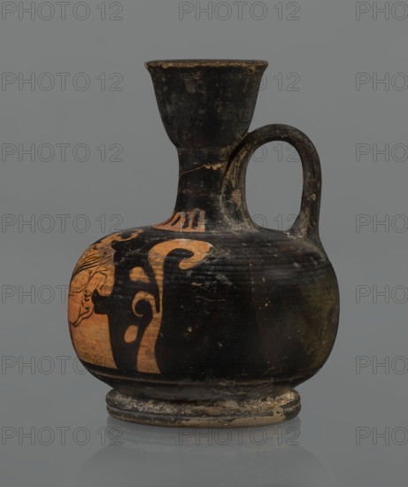 Red-figure aryballos lekythos, unknown Campanian workshop. A squat lekythos with a ring-shaped foot. Belly broad, spherical and flattened; shoulders rounded and broad. Narrow, low neck as high as the rim; cup-shaped rim. Ribbon-shaped vertical handle. Front decorated with a bar ornament at the base of the neck. Belly and arms depict a seated woman facing left: legs in profile left extended, right withdrawn, hips three-quarter en face, arms frontally, head in left profile. Left arm wrapped around a himation, hand resting on the hip; right hand outstretched above a tossed circular object of two light-colored parts ball or skein of wool?, each with a single black dot, separated by a dark stripe. Hair combed back and tied in a bun. Woman wears a necklace and earrings of spherical beads indicated by dots. Sides bear a motif of vertically unwinding plant tendrils with spirally coiled ends. Reddish clay; turning lines visible. Neck diagonally cracked and glued; rim chipped. 2nd half of the 4t...
