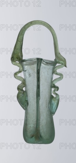 Dilekyt, unknown Eastern workshop Syrian or Palestinian, glass vessel, 3rd century, Roman Empire 27 BC–476, The vessel consists of two tubes connected at one side and a flat bottom. The outer sides are gently curved towards the axis and decorated with two thick glass threads. The wavy threads begin with thickenings at one-third of the vessel's height and terminate at the rings of the slightly flared spouts. At the joints of the threads and spouts, a large bow-shaped vice is supported, wider on one side than the other, narrowed at the top. Height 15.7 cm, width 7.3 cm, depth 2.3 cm., A translucent glass vessel with a tall narrow body and a rounded base in pale green and aqua tones, featuring a looped handle arching from one side to the other in a slightly darker green, and a pair of decorative twisted, ribbon-like side elements with curving, undulating shapes in similar green hues attached near the rim and extending downward; the glass shows small bubbles, irregularities, and areas of s...