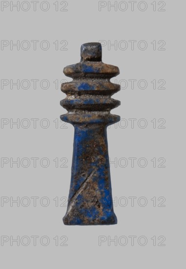Amulet - djed pillar. Djed pillar with four crossbars, decorated on both sides; pendant on top. Late Period–Ptolemaic period, 7th–1st century BC, Egypt. Material: amulet. Dimensions: height 2.5 cm, width 0.8 cm., A single, vertically oriented object with a tapered base and a stacked, ridged top is centered on a plain gray background; the object shows a mottled surface with prominent blue and brown tones, darker brown patches and some lighter worn areas, and a textured, slightly rough appearance with uneven edges and small pits.