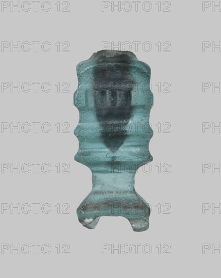 Cosmetic bottle, Islamic, Arabic culture. Thick-walled blue glass vessel with one convex band decorated with fine horizontal grooves, flat arms, heavily carved base with four feet, and wheel-cut decoration. 9th–11th century, Egypt. Height 4.1 cm; width 1.7 cm., A translucent aqua-blue glass object with a symmetrical, ridged profile centered against a light gray background, showing textured surfaces and irregular edges, a darker bluish core visible through the glass, a few tiny air bubbles and surface imperfections, and subtle areas of darker greenish-blue and faint brownish spots near the lower section.