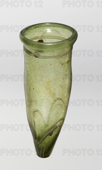 Lamp oil container, deposit provenance, Islamic art, Arabic culture, glass oil lamp, cream enamel thread also at the bottom, 12th–15th century, Syria, / Egypt, Middle East, height 12.0 cm, diameter 5.2 cm, A translucent green glass vessel with a flared round rim and a narrow pointed base, showing a few surface bubbles and small inclusions throughout the glass and a few darker green swirls and irregular streaks inside and along the exterior, with a glossy highlight on the inner rim and a pale neutral background.
