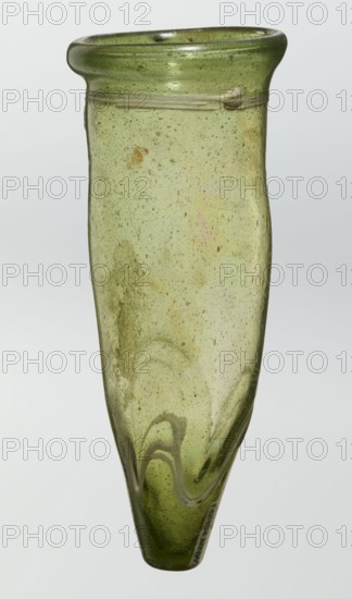 Lamp oil container, deposit provenance, Islamic art, Arabic culture, glass oil lamp, cream enamel thread also at the bottom, 12th–15th century, Syria, Egypt, Middle East, height 12.0 cm, diameter 5.2 cm, A tall, narrow glass vessel with a rounded flared rim, made of translucent green glass showing many small bubbles and surface irregularities, with a slightly darker green band near the top and a pale green body that becomes a deeper green toward the tapered base, featuring a few faint swirl patterns and areas of subtle discoloration.