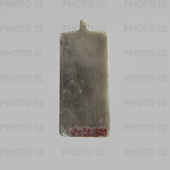 Tile with pseudo-hieroglyphs; scarab with pseudo-hieroglyphs on the base; 20th century; Egypt; forgery; scarab amulet; height 0.9 cm, width 2.4 cm, depth 1.4 cm., A rectangular, slightly worn object with rounded top edges and a small protrusion at the center of the top, shown against a light gray background; the object has a smooth, scratched surface with a metallic gray and brownish tone, subtle darker gray areas, and a few small lighter specks, plus a small area of red near the bottom edge.