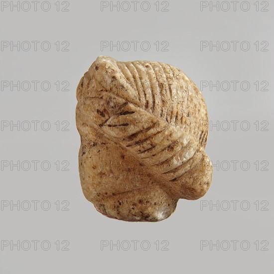 Head of a woman, Roman period, Egypt; figurine; height 5.5 cm, width 3.5 cm, depth 4.5 cm., A small carved object photographed against a pale gray background showing the back and side of a rounded form with textured grooves and carved ridges; the surface appears mottled with shades of beige, tan, cream, and darker brown spots, with a smooth worn appearance and visible striations and indentations suggesting a patterned, wrapped or coiled shape.