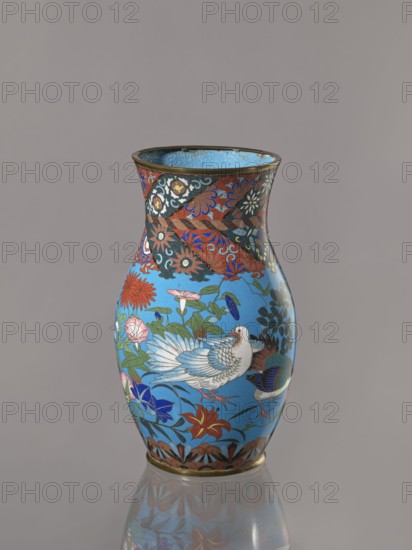 Vase, Vase with a thick neck, parted towards the spout. Cloisonné enamel on copper; the spout and foot are enclosed by brass rings. Decorated with doves, flowers lilies, chrysanthemums, sakura, wolfberries, butterflies, dragonflies, kachôga-style bird-and-flower imagery. Japanese, Meiji period, ca. 1870–1880; Nagoya. Vessel. Height 26.5 cm; width 15.5 cm., A rounded vase with a flared rim stands against a plain neutral background, its surface dominated by a bright turquoise-blue field decorated with a stylized white bird with detailed feathering, surrounded by a profusion of floral motifs and leafy vines in red, pink, green, dark blue, and black; the neck and shoulder feature a contrasting band of ornate patterns in red, black, and gold tones with swirling floral and geometric elements, and the base is edged with a narrow metallic rim and a patterned border in brown and gold; the glossy finish produces a subtle reflection of the vase on the surface beneath it.