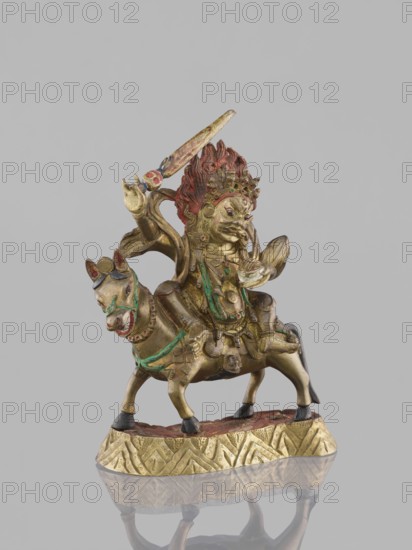 Palden Lhamo, revindication, Tibetan Buddhist art figurine, Tibetan culture; Choynowski, Józef; Buddhist art depiction of dharmapala with mules and skulls; Dawidow, Alexander Petrovich; 19th century; China, or Mongolia ; sculpture; height 14.8 cm, width 13.0 cm, A small metallic statue depicts a figure riding an animal, both mounted on a decorative base; the sculpture shows a few areas of red, green, gold, black, and hints of blue, with the rider featuring a prominent red mane and gold facial details, the animal mostly gold with green accents and black hooves, and the base showing gold with reddish-brown on top, all set against a plain light gray background.