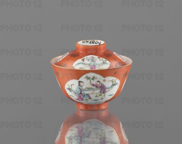Bowl with a lid, ceramics, colored porcelain, Qing dynasty Tongzhi, 1862–1874, China; subject: bats and swastikas loosely placed in the background of the decoration, genre scenes; inscriptions: hieroglyphs; vessel; height 8.6 cm, diameter 10.3 cm; Chinese art., An orange ceramic bowl with a lid sits centered on a reflective gray surface, showing a reflection beneath it; the bowl has white cloud-shaped panels decorated with painted figures in pastel colors including light blue, pink, purple, green, and flesh tones, and small decorative motifs in gold on the orange background; the lid has a short orange neck and a white interior rim, and the overall scene is set against a plain gray background.