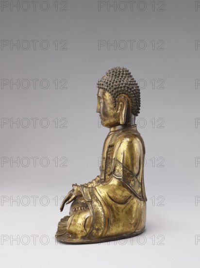 Buddha, deposit provenance, militia deposit, Chinese art, Chinese culture, Qing 1644–1911, Qing style, sculpture, casting, Chinese Buddhism, Buddhist art, Ushnisha, 19th century, China, figurine; height 32.0 cm, width 23.5 cm, weight 6.255 kg, A gilded metal statue of a seated figure shown in profile against a neutral gray background, with a textured hair surface in dark gray and the rest of the figure in gold tones; the figure wears a patterned robe with darker decorative inlays along the edges and sits with hands resting in the lap, showing sculpted folds in the clothing and stylized details on the ears and face, with a flat base that the figure rests upon.
