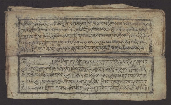 Buddhist text - Formula of Repentance Tib. sdig bshags gser gyi spu gri bzhugs so, author unknown. Book in the Tibetan pecha style; xylographic print in the disciple script dbu can. 16 folios folio numbering 2–15 recto, first verso. Print on thin handmade paper, clear translucency. 19th century, Tibet. Graphic prints; Buddhist art; Tibetan. Dimensions: width 25.5 cm, height 7.8 cm., A rectangular sheet with worn, textured paper rests against a dark background; the paper is off-white to beige with areas of light brown discoloration and darker stains, and it appears creased and slightly frayed at the edges. Two bordered horizontal panels occupy the sheet, each containing dense, flowing handwritten strokes in dark ink that form repeating linear patterns across the panels; the ink ranges from deep black to faded gray in places. Narrow black borders frame each panel, with a thicker horizontal band separating them that shows smudging and uneven ink. The left edge of the sheet shows a folded ...