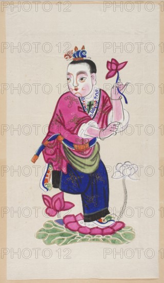 Boy on a lotus leaf with a lotus in his hand; creator, nianhua New Year's picture, Chinese, early 20th century; graphic print; height 51.0 cm, width 29.0 cm; lotuses., A painted figure stands on a green and pink stylized lotus base, wearing a bright pink robe with swirling decorative patterns and dark blue trousers with gold detailing; the figure has pale skin with rosy cheeks and dark hair pulled back under a small ornate headdress in blue and orange, and holds a pink lotus flower with a blue stem in one hand while the other arm is bent with a white sleeve showing; additional pink lotus blossoms appear near the feet and to the side, and the shoes are pink and white with green and orange accents, all set against a mostly off-white background with a beige border.