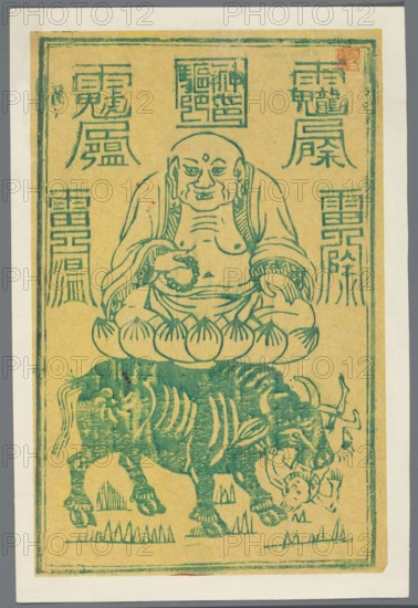 Buddha Mi Le Fo Maitreya sitting on a bull, amulet print, nianhua New Year's picture, print serving as an amulet against illness, early 20th century, China, Chinese art, buddha iconography, amulets, bulls, graphic print, graphic, height 25.6 cm, width 17.1 cm, The image shows a printed illustration in teal on a yellowed background bordered by an off-white mat; a seated, bald figure with visible facial features and a dot on the forehead sits cross-legged on a stylized lotus cushion, wearing draped robes and holding a beaded object in one hand while the other hand rests on the knee; below the cushion is a large, sturdy animal with curved horns and a textured body standing on a patch of grass, and a small humanlike figure is depicted near the animal's mouth; the composition includes decorative rectangular motifs and vertical column-like designs along the sides in the same teal color.