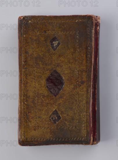 Quranic manuscript, unknown creator/calligrapher, ; Islamic art, Ottoman dynasty 1299–1922; Arabic manuscript in Naskh script, illuminated, two pages for Surah XVII, with sixteen later leaves; paper striated, smoothed, cream and saffron-colored; 18th century, with 19th-century additions; Central Asia origin, Khiva; manuscript dimensions: height 23.0 cm, width 14.5 cm, thickness 4.2 cm., A rectangular object with a worn surface in shades of brown and dark reddish brown, showing a central dark reddish-brown diamond-shaped patch and two smaller dark diamond accents above and below; the edges display darker brown and reddish tones with visible wear and scuffing, and the surface has decorative incised borders and a few subtle scratches and spots.