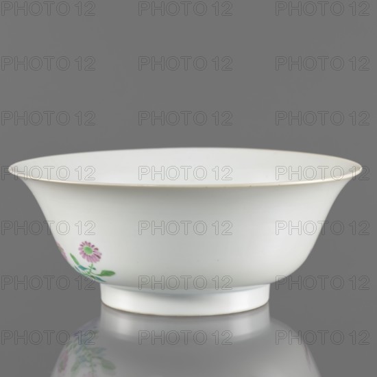 Bowl, ; Chinese; Qing dynasty, Yongzheng period 1723–1735. Porcelain with white transparent fritted glaze; decoration painted with overglaze enamel paints depicting peonies and rocks. Semicircular body widening toward the upper edge. Vessel, height 7.6 cm, diameter 19.5 cm, weight 0.3 kg., A smooth white porcelain bowl with a flared rim and a short foot sits against a gray background, showing a delicate painted floral motif in shades of pink and green on one side and a thin pale gold line along the rim; the bowl and its floral reflection are visible on the glossy surface beneath.