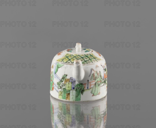 Teapot with lid, ceramics, figurative scenes, Paderewski, Ignacy Jan 1860-1941, gardens, Chinese art, Chinese culture, colored porcelain teapot, porcelain fragment; white, transparent glaze. Decoration painted with overglaze enamel paints and iron red. 19th century, China. Vessel; height 8 cm, width 14.3 cm, diameter 9.3 cm., A small rounded ceramic teapot with a short spout and a lid sits on a reflective surface, showing a mirrored reflection beneath. The teapot is predominantly white with painted scenes and decorative patterns in green, orange, yellow, blue, and black. One side shows a figure wearing a green robe, and other painted figures and architectural shapes appear around the body. The lid has a small white knob and a patterned band with green and yellow geometric details, and there are floral or decorative accents in orange and green on the top. The background is a uniform gray.