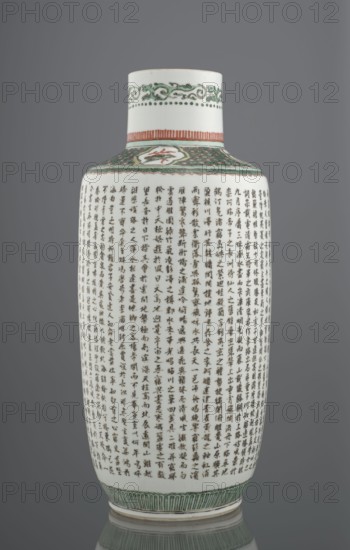 Vase, from Ignacy Jan Paderewski; Chinese, Qing dynasty 1644–1911; ceramics, colored porcelain; Bangping vase from the green family; cylindrical with a shortened neck on a wide, flat ring foot; decorated with Wang Bo's text Prologue to the poem on the pavilion of Prince Teng and a landscape composition depicting the pavilion and its surroundings; architectural and plant motifs; 19th century, China; vessel; height 40.4 cm, diameter 17.8 cm, weight 2.7 kg., A tall cylindrical porcelain vase sits against a neutral gray background, showing a smooth white surface decorated with dense narrow vertical rows of dark brushwork covering most of the body; the shoulder and neck feature a band of green scrolling patterns and dotted accents, a narrow band of reddish-orange vertical strokes, and a patterned green collar with a small medallion that includes a hint of red. The base rim displays a band of vertical green petal-like motifs, and the overall visible colors include white, dark brown or black ...