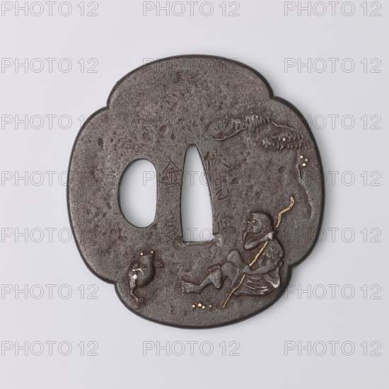 Crossguard tsuba, Kaneie craftsman, Edo period 18th century, 1603–1868, Japan — Fushimi, Yamashiro. Tsuba in the shape of a quatrefoil mokkô with an uchikaeshi edge, katahitsu ana one side hole. Relief decoration showing the sennin Gama sitting under a tree, holding a staff and looking at a three-legged frog; reverse with a sketched landscape motif with a waterfall. Details eyes, pebbles, staff inlaid with gold and shakudô. Materials: metal shakudô inlay. Function: sword crossguard katana. Height 7.2 cm, width 6.8 cm, depth 0.4 cm., A dark brown, roughly cloud-shaped metal object with a textured surface and two irregular cutouts, showing a carved scene of a seated figure holding a curved staff and a nearby frog-like creature; small inlaid dots of gold highlight parts of the staff, the creature’s eyes, and a few scattered spots on the surface, and there are lighter brown and subtle reddish-brown variations across the metal.