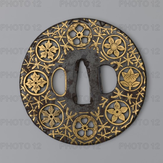 Crossguard tsuba, sword crossguard of maru gata round tsuba mon-sukashi type, decorated with eight openwork coats of arms monami arranged around the edge against a background of a brass-inlaid stylized vine karakusa. Katana fitting, edged weapon. Japanese, Edo period, 17th century. Tsuba; diameter 8 cm, thickness 0.3 cm., A round ornate metal object with a dark brown surface inlaid with gold floral motifs and a few circular cutouts, featuring a central vertical opening flanked by two elongated openings, decorated around the rim with several stylized flower designs and scattered gold linear accents on a gray background.