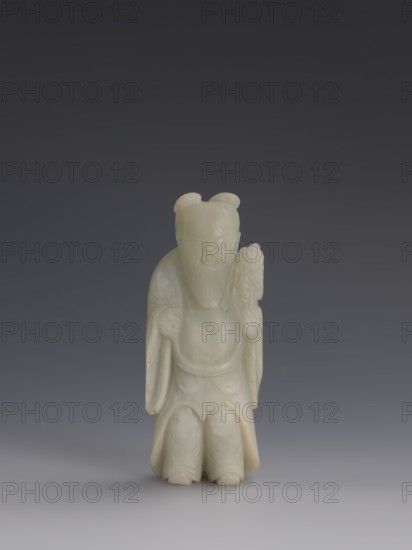One of the Eight Immortals;, iconography: Eight Immortals; subject: men; culture: Chinese; fan; Qing dynasty 1644–1911, 19th century, China; sculpture; height 14.3 cm, width 5.9 cm., A small carved figurine made of pale greenish-white stone stands on a smooth surface against a dark gray to bluish gradient background, showing a robed figure with a long beard and a rounded hair bun on each side of the head, holding a fan-like object in one hand and draped sleeves over the other hand, with carved folds in the robe and rounded feet visible at the base; colors visible include pale greenish-white, gray, dark gray, and bluish-gray.
