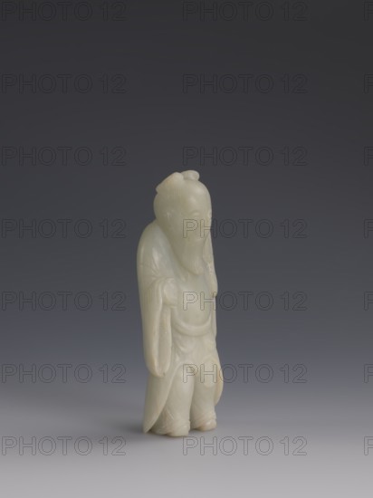 One of the Eight Immortals;, iconography: Eight Immortals, men; Chinese art; Qing dynasty 1644–1911, 19th century, China; sculpture; height 14.3 cm, width 5.9 cm., A standing carved figure made of pale greenish-white stone with smooth, rounded surfaces and a slightly glossy finish, depicting a person with a long beard and hair gathered at the top of the head, wearing flowing robes with draped sleeves and layered folds; the figure's facial features are gently modeled with closed or downcast eyes and a subtle expression, and the hands are partially concealed by the sleeves; the base shows the figure's feet peeking from beneath the robe. The background is a smooth gradient ranging from dark gray at the top to lighter gray toward the bottom. The visible colors are pale greenish-white, gray, and subtle off-white tones.