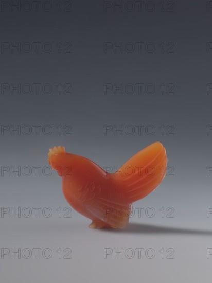 Hen; creator, sculptor; ; Chinese; Qing dynasty 1644–1911; figurine of a hen; 18th–19th century; sculpture; materials: Chinese art; dimensions: height 4.5 cm, width 5.0 cm, depth 2.3 cm, A small carved bird figurine with a smooth glossy surface in shades of orange and red stands on a flat surface, showing carved feather details and a raised tail, casting a soft shadow on a neutral gray background that gradates from darker at the top to lighter toward the bottom.