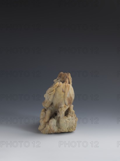 Buffalo with calves and shepherds, unknown sculptor, buffaloes, Chinese art, figurines, Chinese culture, Qing 1644–1911, sculpture made of decorative stone from the Fushan Mountains in Zhejiang Province soapstone, full, natural patina, 18th–19th century, China, sculpture, height 16.5 cm, A small carved sculpture sits on a smooth surface against a gradient background; the sculpture is primarily beige and tan with areas of darker brown veining and subtle yellowish tones, and it depicts an organic, rounded form with flowing, layered shapes and several protruding limb-like elements emerging from a textured base, showing smooth and slightly worn surfaces with shadows and highlights emphasizing its contours.