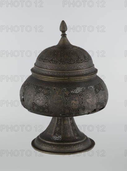 Censer, Persian Iran, Qajar dynasty 1785–1925, 18th/19th century. Censer, height 33.0 cm, diameter 22.0 cm. Islamic art; figurative scenes of hunting, acrobatics, riders; decoration with human figures, animals, demons in cartouches, dense arabesque background, plant motifs, fantastic creatures dragons, beasts, fantasy scenes., An ornate metal vessel with a rounded, domed lid topped by a pointed finial sits on a flared pedestal base; the surface shows intricate openwork and pierced patterns with decorative bands and panels, and the metal appears in shades of dark brown and muted gold with areas of darker patina.