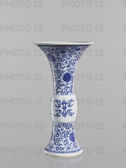 Gu-type vase, ; blue-and-white porcelain, Qing dynasty 1644–1911, early 19th century, China; motif: lotuses and lotus tendrils; backdated signatures; vessel, height 22.6 cm, diameter 12.2 cm., A tall porcelain vase with a flared rim, a narrow waist, and a slightly flared base, decorated all over in blue on white with intricate scrolling vine motifs and stylized flower medallions, including a smooth rectangular midsection bearing a symmetric ornamental design; the visible colors are blue and white, set against a neutral gray background.