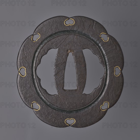 Crossguard tsuba, Kasuga school; maker: Kunihide. Tsuba in the shape of an eight-petaled flower hachi mokkô; both hitsu cut into an identical multi-petaled shape. Central part enclosed by a fairly wide, recessed circle stained with dark red lacquer, with openwork heart-shaped cutouts inome type at the edge between the petals, emphasized by delicate gold inlay. Surface partly of the mokume tetsu type imitation of wood grain. 17th century Edo period, 1603–1868. Japan, Higo province. Materials: tsuba iron. Diameter 8 cm; thickness 0.25 cm., A dark brown, round metal object with a scalloped outer edge and a recessed inner ring, showing a central cutout with curved openings on each side and a vertical central slot; several small heart-shaped cutouts along the scalloped rim are outlined in gold, and there are visible textures and subtle variations in brown and black on the surface against a plain gray background.