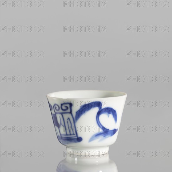 Bowl, ceramics, blue and white porcelain, Qing style, Chinese art, Chinese culture, landscapes with architecture, landscapes with staffage, landscape motifs, Qing 1644–1911, porcelain pottery, grayish-white. Bowl with flared edges on a low ring foot, 19th century, China; vessel; height 4.4 cm, diameter 5.8 cm., A small white porcelain cup with blue painted designs around its exterior, showing a few curved brushstrokes and decorative motifs, set against a plain light gray background and resting on a reflective surface that mirrors the bottom of the cup; visible colors include white, blue, light gray, and a hint of darker gray in the reflection.